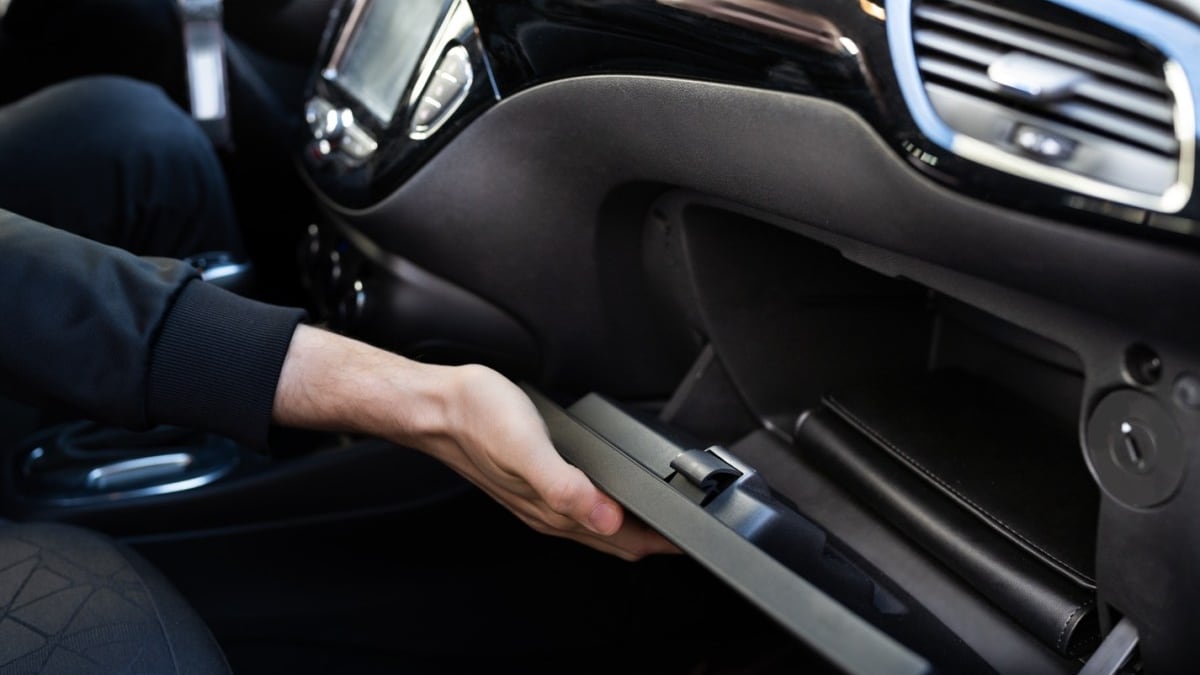 Mann öffnet das Handschuhfach im Auto